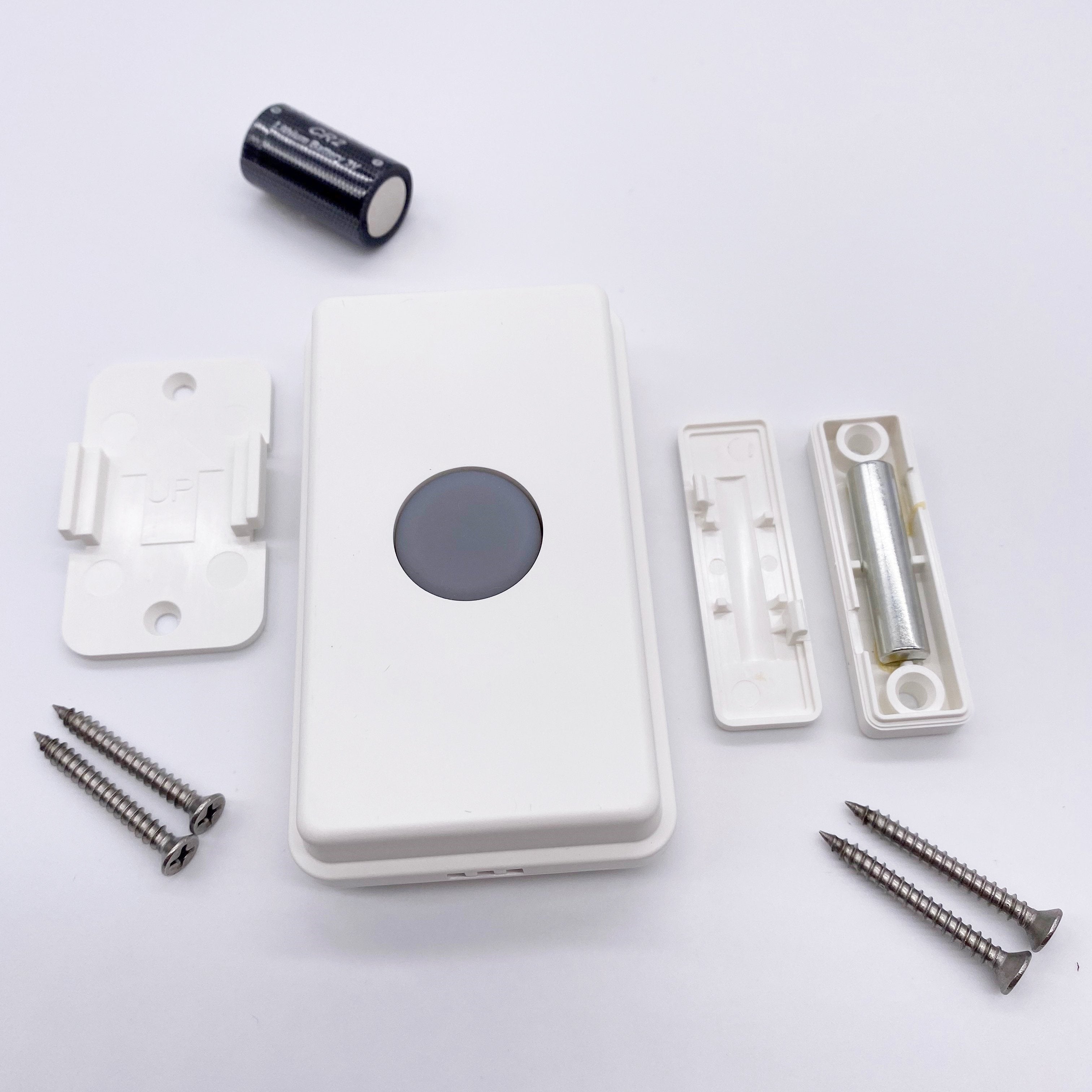 wireless push button showing mounting hardware and battery